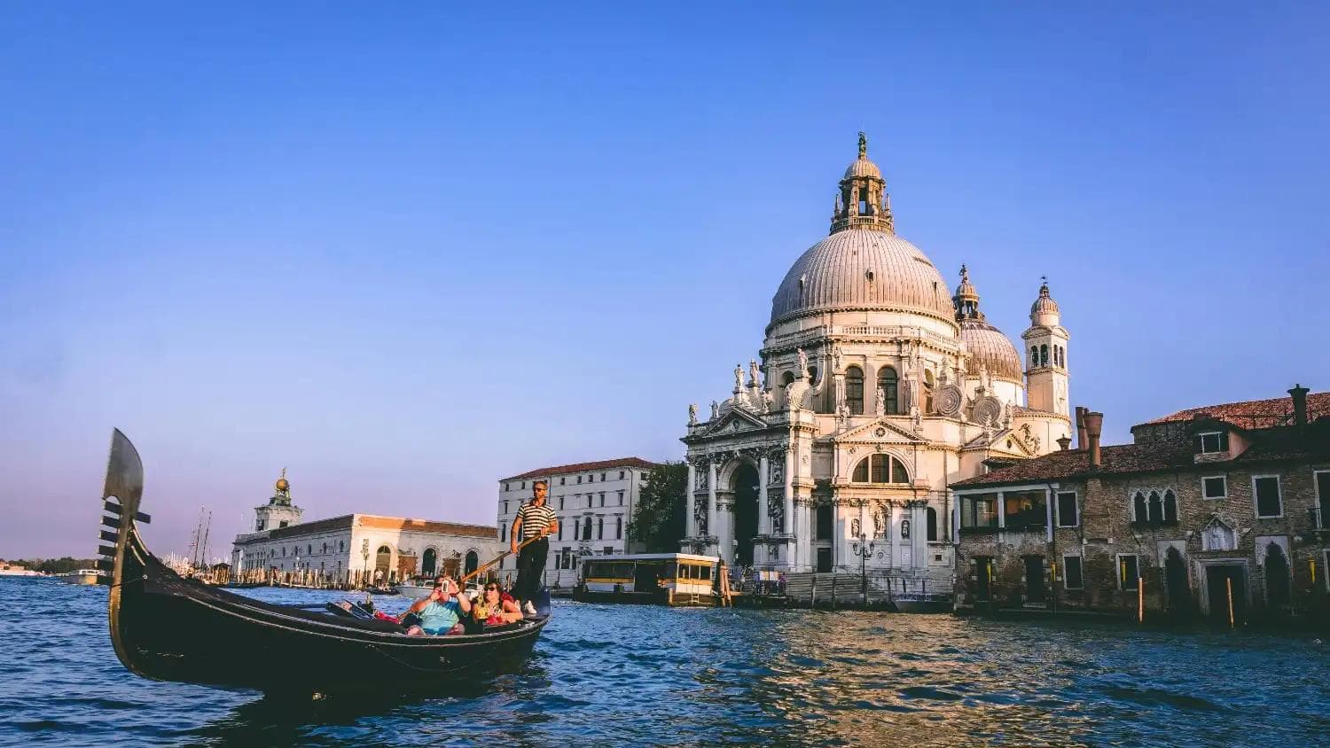 Tourists enjoying a gondola ride near the historic Basilica di Santa Maria in Venice, an iconic spot like top places to visit in Singapore.