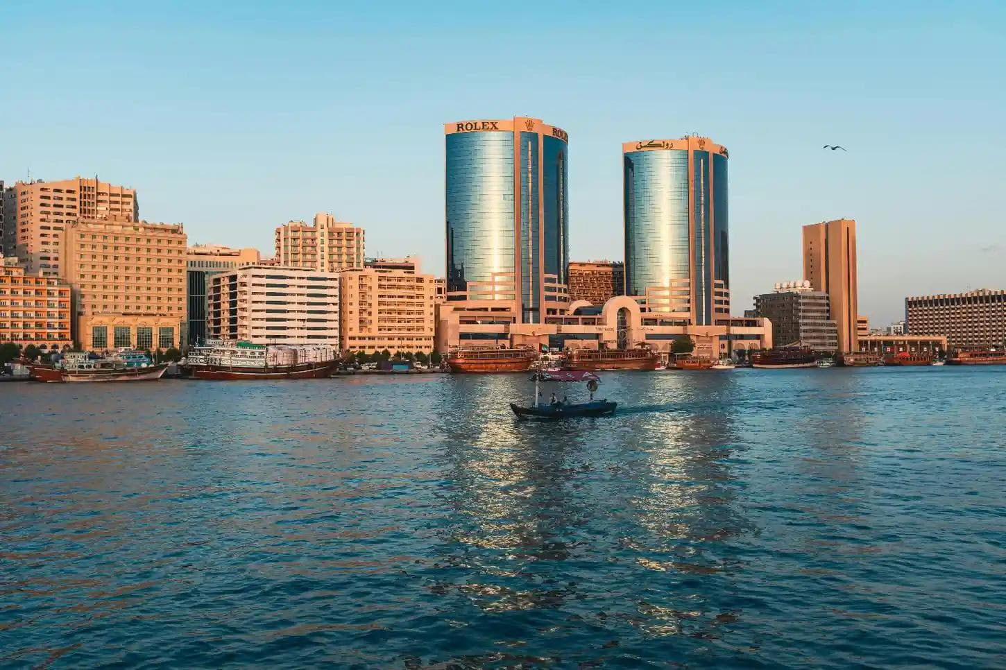 Traditional Abras on Dubai Creek with the iconic Rolex Twin Towers. Best Old Dubai tour with best dubai tour packages, historical places, UAE sightseeing, city trip.